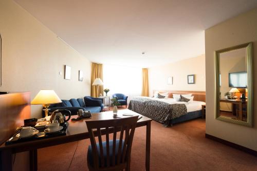 a hotel room with a bed and a living room at Carathotel Basel/Weil am Rhein in Weil am Rhein