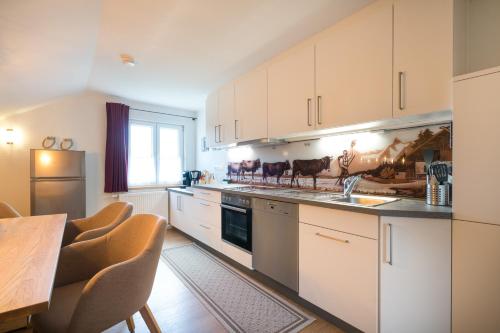 a kitchen with white cabinets and a table with chairs at Ferienwohnungen Alpentraum - Gerstruben in Fischen