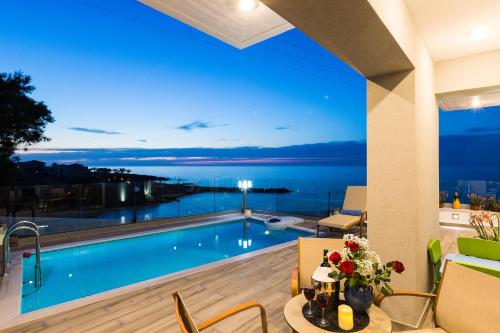 a swimming pool with a view of the ocean at night at Contessa Del Mare in Panormos Rethymno