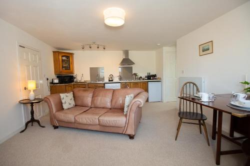 a living room with a couch and a table at PERFECT BUSINESS ACCOMMODATION at SIDINGS FARM - Luxury Cottage Accommodation - Self Catering - Secure Parking - Fully equipped Kitchen - Towels & Linen included in Pidley