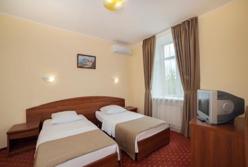 a hotel room with two beds and a tv at Maxima Zarya Hotel in Moscow