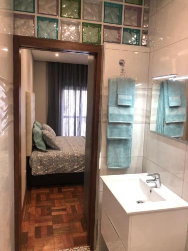 a bathroom with a sink and a bed and a mirror at OPORTO APARTMENT LUXURY in Porto
