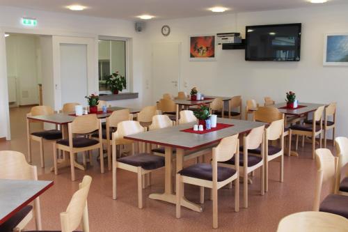 a dining room with tables and chairs and a flat screen tv at Sportpension Dresden in Dresden