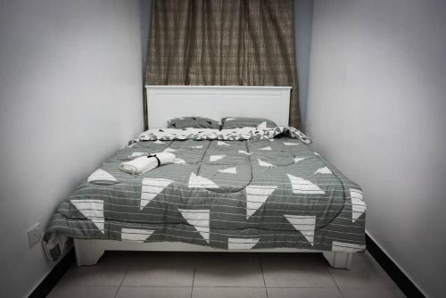 a bedroom with a bed with a gray and white comforter at 80'S PARADISE in Tanah Rata