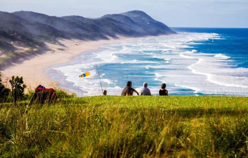 a group of people sitting on a hill looking at the beach at Sky Island Resort in Ponta Malongane