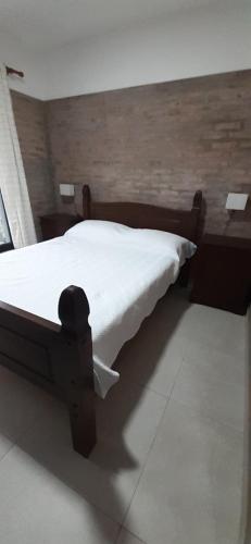 1 dormitorio con cama de madera y edredón blanco en Los Cardenales 3, en Pajas Blancas