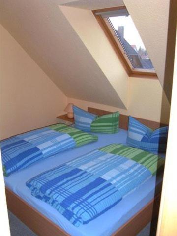a bedroom with a bed with blue and green pillows at Ferienwohnung Köhler in Glowe