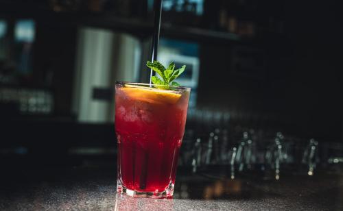 a red drink sitting on a bar with a green garnishment at Pflegehotel Sutz-Lattrigen in Sutz-Lattrigen
