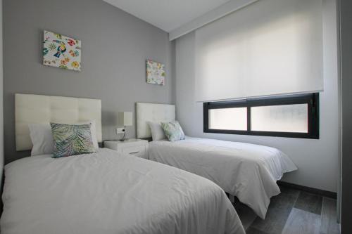 ピラール・デ・ラ・オラダダにあるHiguericas Costa 412 - Rooftop terrace and pool view 300 m from beachのベッドルーム1室(ベッド2台、窓付)