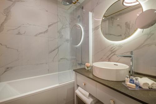 a bathroom with a sink and a mirror at Hôtel Le Walt by Inwood Hotels in Paris