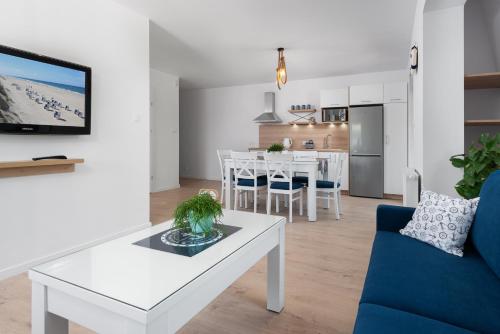 ein Wohnzimmer mit einem weißen Tisch und einem blauen Sofa in der Unterkunft Apartament Biała Kotwica in Jastrzębia Góra