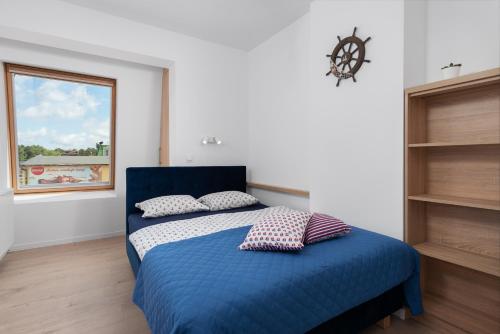 a bedroom with a blue bed with two pillows at Apartament Biała Kotwica in Jastrzębia Góra