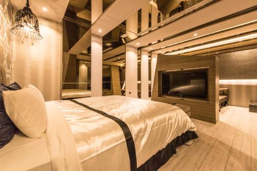 a bedroom with a bed and a flat screen tv at Voga Motel in Taichung