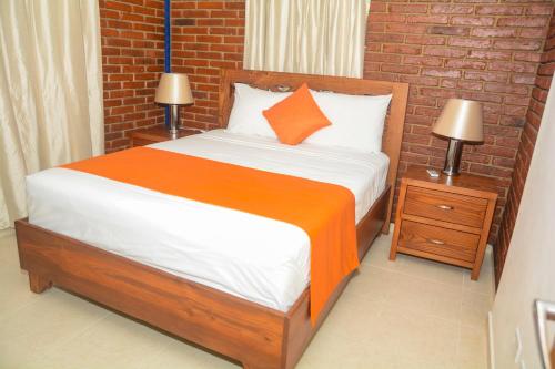 a bedroom with a bed and a brick wall at Hotel Jaraba in Jarabacoa