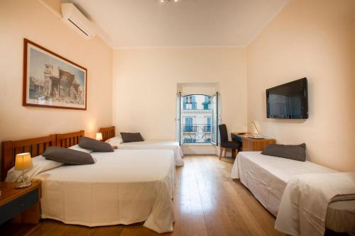 ローマにあるTourist House B&Bのベッド3台とテレビが備わるホテルルームです。
