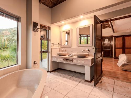 a bathroom with two sinks and a bath tub at Ivory Tree Game Lodge in Pilanesberg