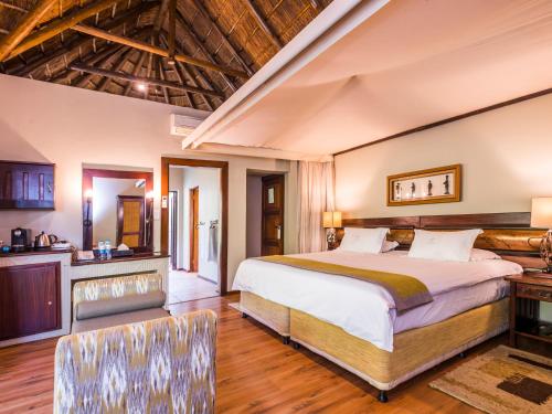 a bedroom with a large bed and a kitchen at Ivory Tree Game Lodge in Pilanesberg