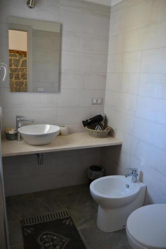 a bathroom with a sink and a toilet and a mirror at Borgo Marinaro La Medusa Arbatax - camera matrimoniale con bagno privato- in Àrbatax