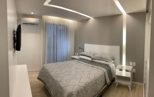 een kleine slaapkamer met een bed en een televisie bij Chartres Charming Residence in Fortaleza