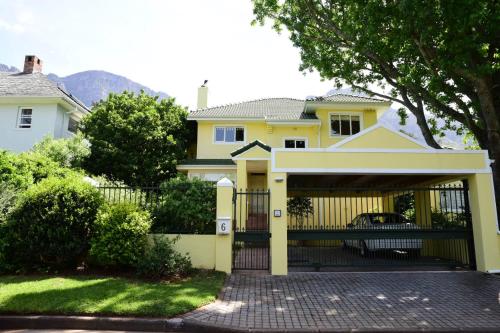 a yellow house with a gate and a fence at On Pinewood Guest House in Cape Town