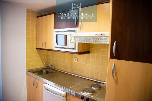 een kleine keuken met een wastafel en een magnetron bij Marina Beach Appart Hôtel in M'diq