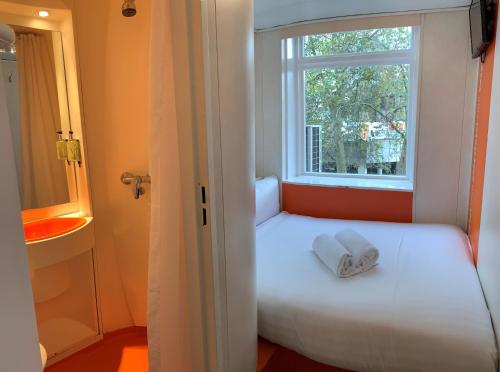 a white bed sitting in a bedroom next to a window at easyHotel South Kensington in London