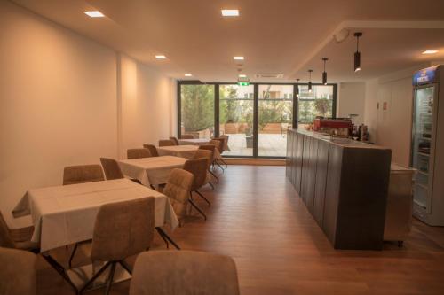 a dining room with tables and chairs and windows at Qama Hotel in Pristina