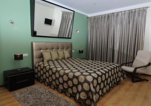 a bedroom with a bed and a chair and a mirror at Hotel S. Jorge in Batalha