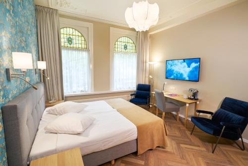 Cette chambre comprend un lit, un bureau et des chaises. dans l'établissement Hotel Van Walsum, à Rotterdam