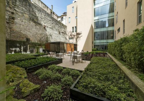 a garden with tables and chairs next to a building at Moov Hotel Porto Centro in Porto