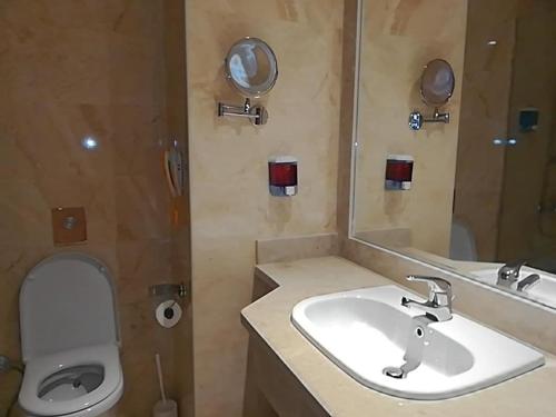 a bathroom with a sink and a toilet and a mirror at Hawaii Caesar Dreams Resort and Aqua Park - Families and Couples in Hurghada