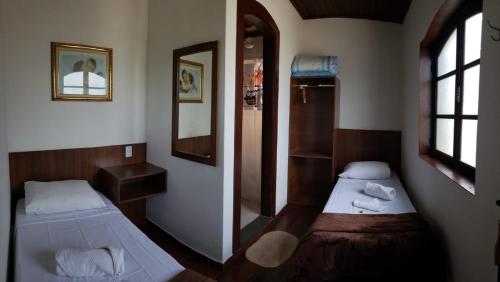 a small room with two beds and a mirror at Hotel Casa Blanca in São Lourenço