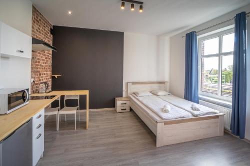 mały pokój z łóżkiem i kuchnią w obiekcie Black & White Vision Apartment - Centrum w mieście Opole