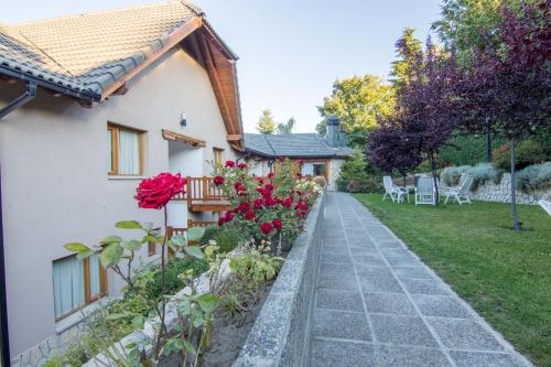 a house with a garden with flowers and a pathway at Apart Altos Del Nahuel in San Carlos de Bariloche