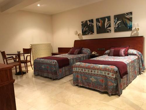 a bedroom with two beds and a table and a dining room at Hotel Suís in Sant Celoni