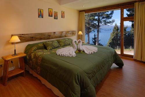 Dos cisnes en una cama verde en un dormitorio en Lejano Nahuel en San Carlos de Bariloche