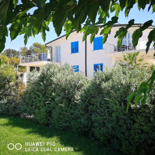 a house with blue windows and bushes in front of it at Appartamenti San Lorenzo Marzamemi Cecilia in San Lorenzo