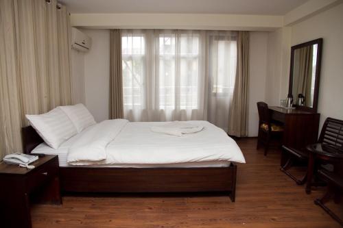 a bedroom with a bed with white sheets and a window at Hotel Yambu kathmandu in Kathmandu
