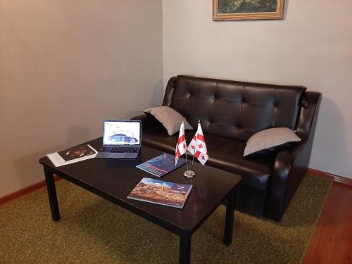 a coffee table with a laptop on a leather couch at Hotel Liva in Mtskheta