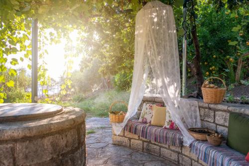 a garden bench with a mosquito net on a stone wall at Liodentro - Olea in Plataria
