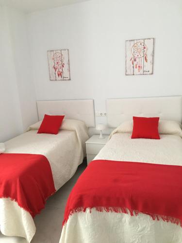 two beds in a room with red and white sheets at TURISMO LOS LANCES TARIFA( PARKING GRATUITO) in Tarifa