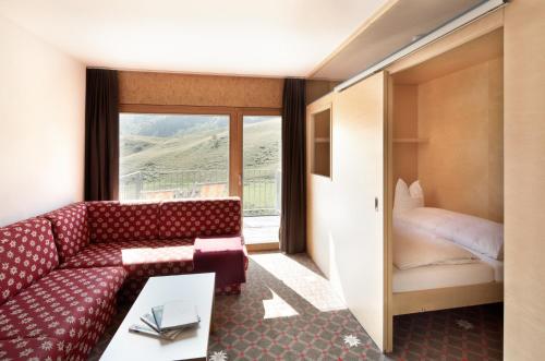 a living room with a couch and a bed at Hotel Adler in Warth am Arlberg