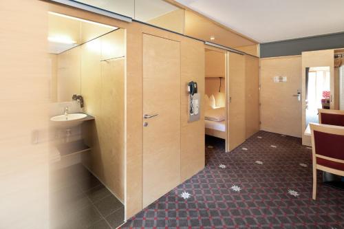 a bathroom with a sink and a room with a bed at Hotel Adler in Warth am Arlberg