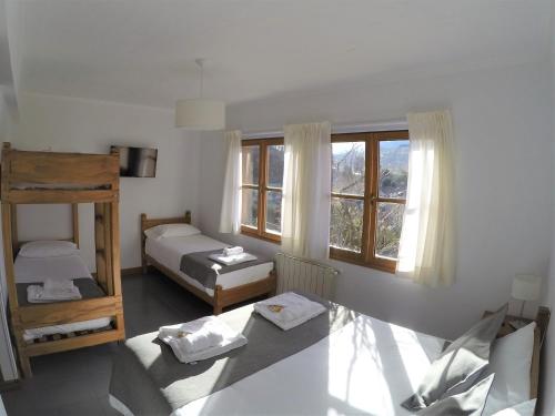 a small room with two beds and a window at Hostería Bärenhaus in San Martín de los Andes