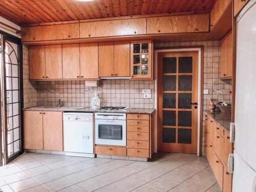 una cucina con elettrodomestici bianchi e armadietti in legno di Agridia View House a Limassol