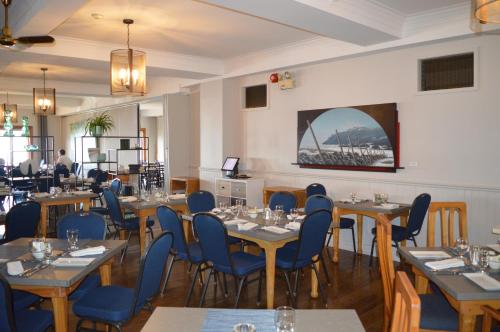 a dining room with tables and blue chairs at Hotel Cap-aux-Pierres in L'Isle-aux-Coudres