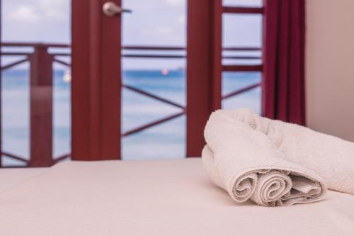 a towel sitting on a bed in front of a window at The Old Gin House Hotel in Oranjestad
