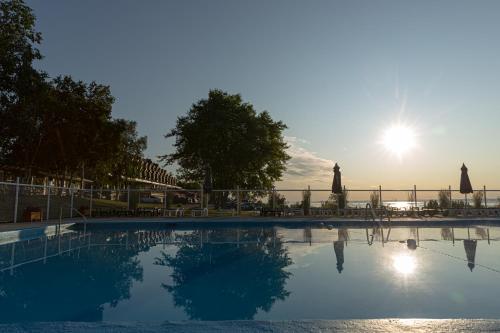 a large swimming pool with the sun in the background at Hotel Cap-aux-Pierres in L'Isle-aux-Coudres