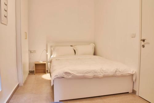 a white bedroom with a white bed with white sheets and pillows at Roza Apartment in Tel Aviv