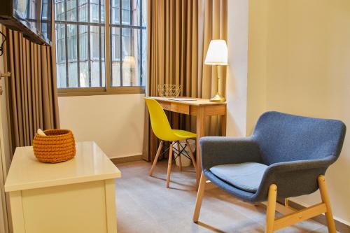 a room with a chair and a table and a desk at Roza Apartment in Tel Aviv